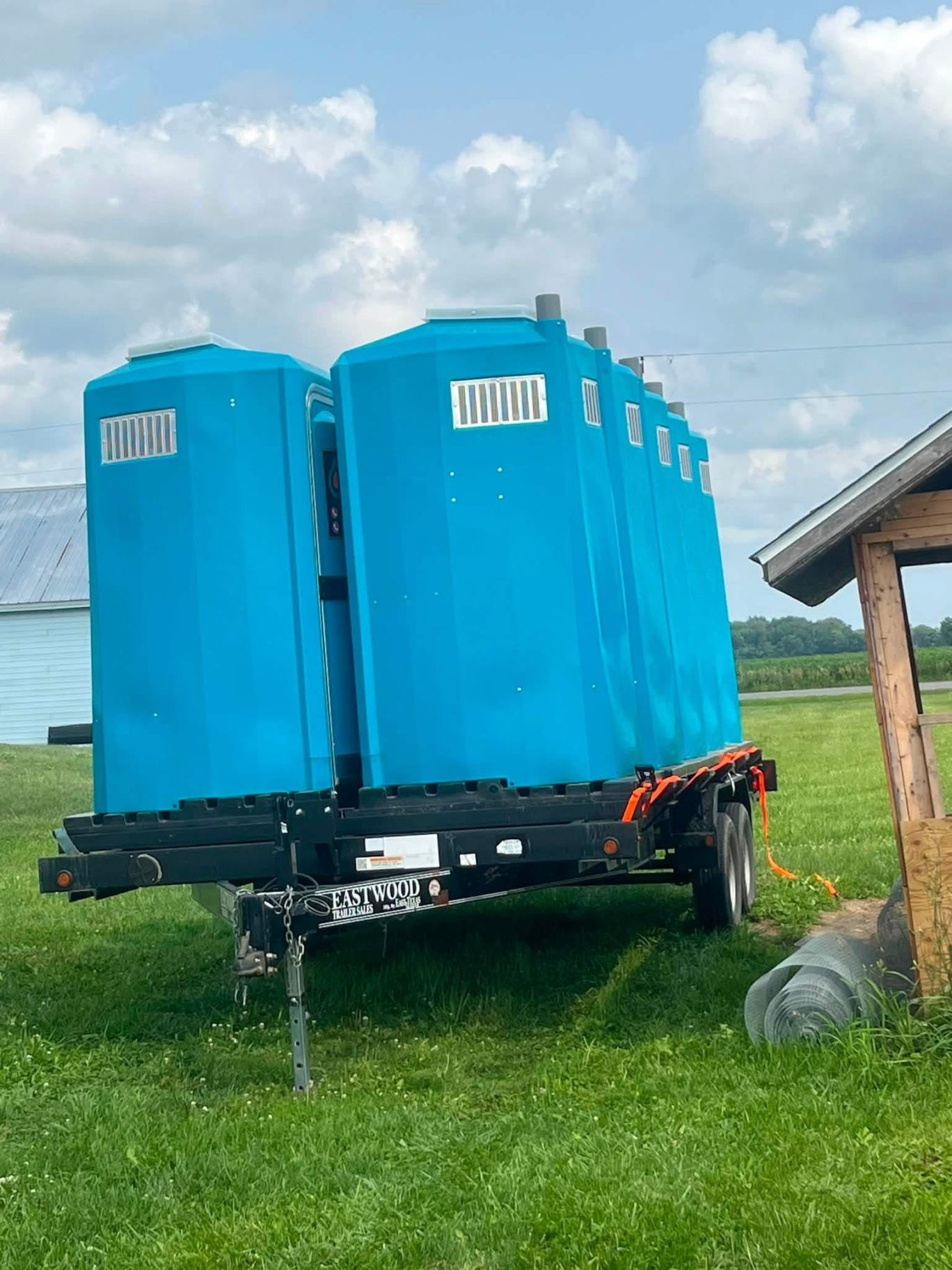 Multiple teal portable restrooms loaded on a trailer