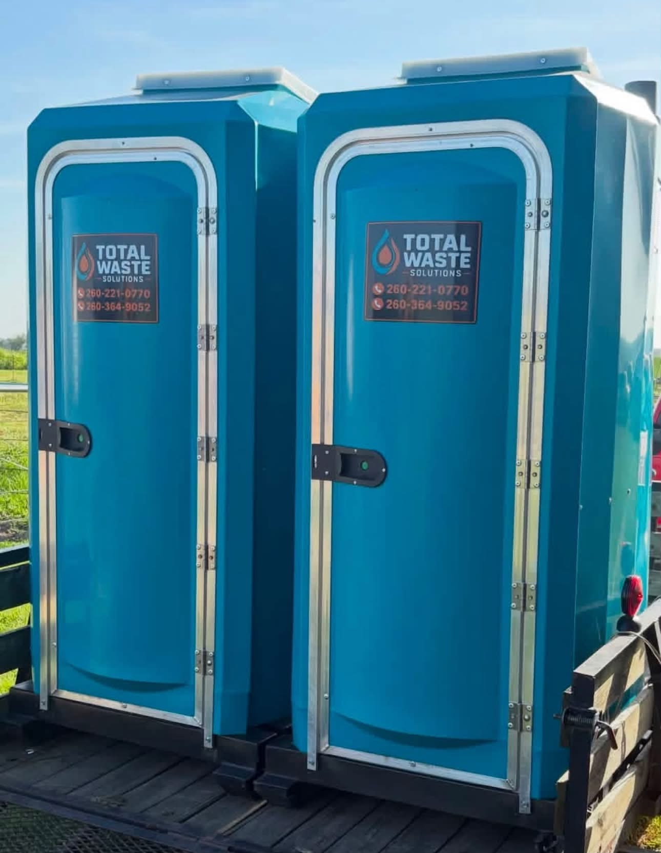Two branded Total Waste Solutions portable restrooms on a trailer